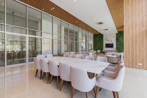 Une salle de conférence moderne dotée d’une grande table et de chaises, de murs en verre, d’un mur végétal et d’un téléviseur à écran plat.