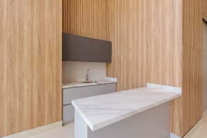 Une cuisine moderne avec un lambris en bois, un plan de travail en marbre et un évier encastré.