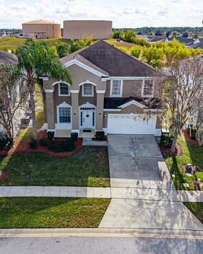 A single-story house with a front garage, a well-maintained lawn, and a driveway. - Magic Palms House | 10 minutes to the parks   (Kissimmee)