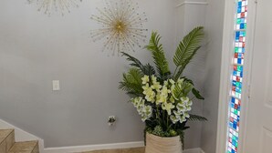 Un couloir agrémenté d’une plante en pot, d’un élément décoratif mural et d’une fenêtre à vitraux.