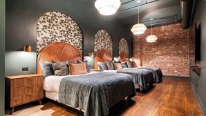 Une chambre moderne avec deux lits, un mur en briques et un plancher en bois.