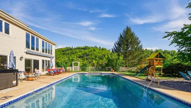 A swimming pool with a wooden deck, lounge chairs, and a play structure. - Sleeps 20 | Sport Court | Game Room | Sauna | Spa (Asheville)