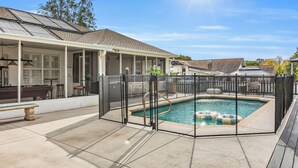A covered outdoor pool area with a pool, a barbecue, and a patio with a table and chairs. - Poolside Paradise - 3 BR with Game Room & Pool Table! (Ocala)