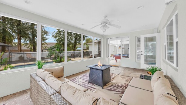 A sunlit patio with a fire pit, outdoor seating, and a view of the backyard. - Poolside Paradise - 3 BR with Game Room & Pool Table! (Ocala)
