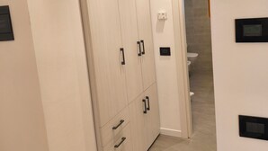 Ein Flur mit einem großen Kleiderschrank, einer Tür zum Badezimmer und einem Thermostat an der Wand.