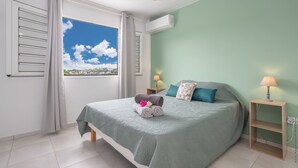 Un dormitorio con cama, ventana con vistas, mesita de noche y aire acondicionado.