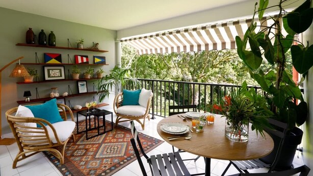 Un espace de restauration extérieur accueillant, avec des meubles en osier, un tapis à motifs et une variété de plantes en pot.
