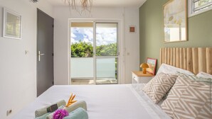 Une chambre à coucher avec un lit, une table de chevet, une fenêtre et une vue sur la verdure.
