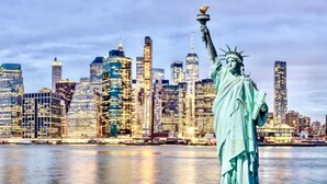 A Estátua da Liberdade com a silhueta de uma cidade ao fundo.