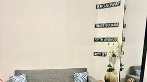 Uma sala de estar com um sofá cinza, uma mesa de centro de madeira e um espelho na parede.