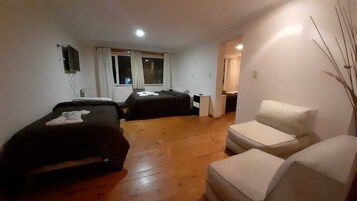 Habitación de hotel con dos camas, un escritorio pequeño, una silla y un ventanal con cortinas.