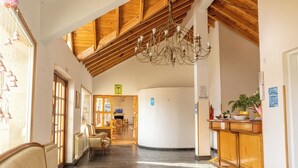 A spacious hotel lobby with a high wooden ceiling, a chandelier, and a reception desk. - ORIPLATA (Caviahue)