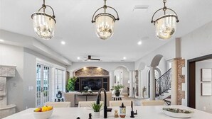 Una cocina amplia con una isla grande, electrodomésticos modernos e iluminación elegante.