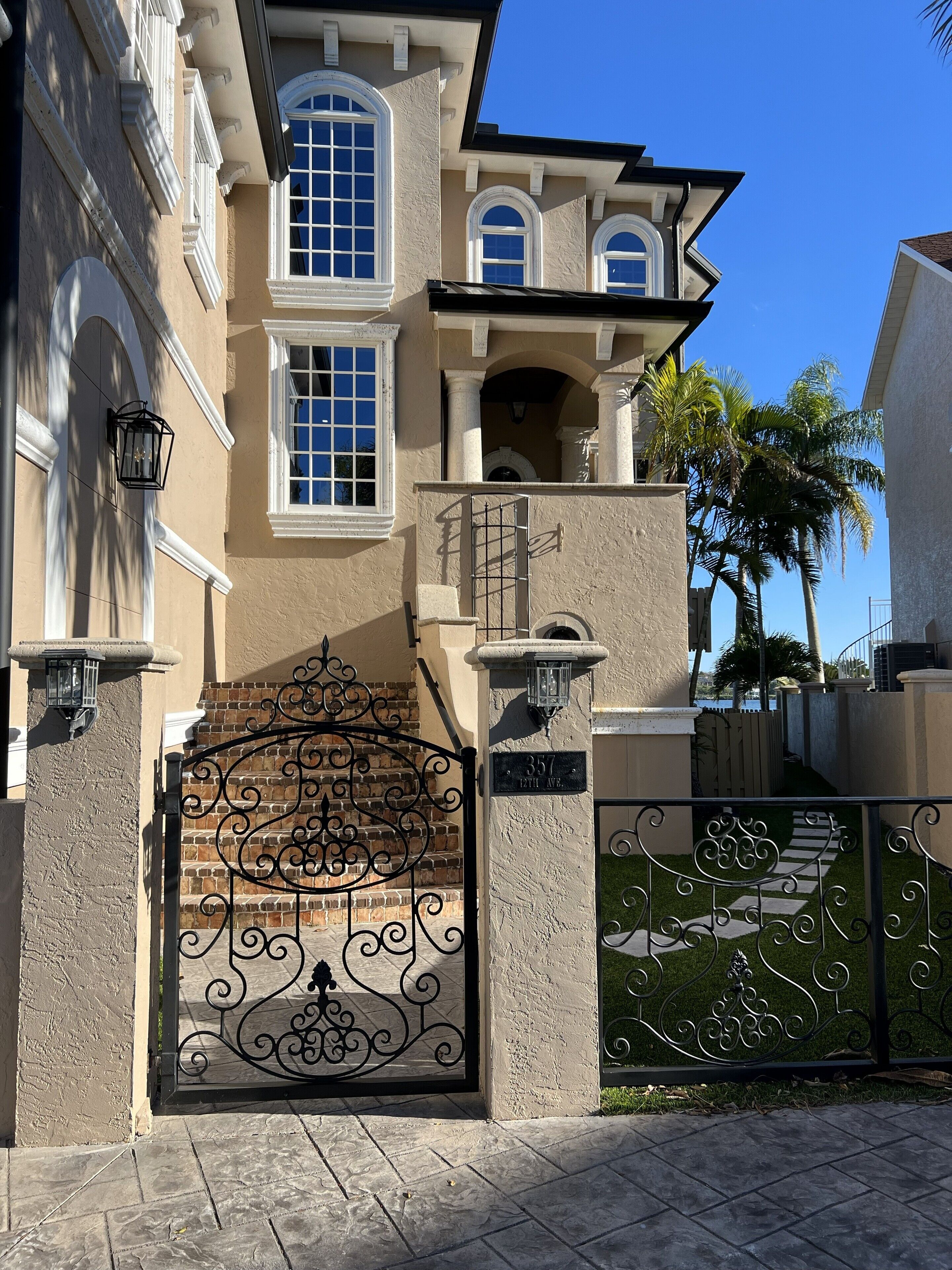 A stately building with a large ornate gate, a brick facade, and a clear blue sky.