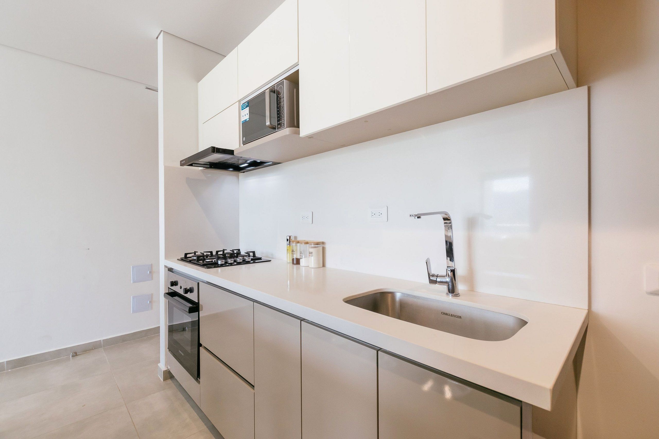 A modern kitchen with a gas stove, oven, microwave, and stainless steel sink.