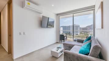 Una sala de estar moderna con un televisor de pantalla plana, un sofá y una mesa de centro.
