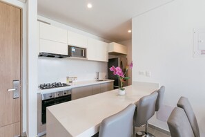 Een moderne keuken met een gasfornuis, magnetron, oven en een eethoek met stoelen en een vaas met bloemen.
