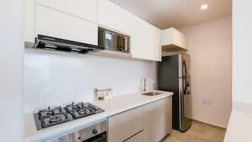 Una cocina moderna con estufa a gas, horno, refrigerador de acero inoxidable y alacenas blancas.