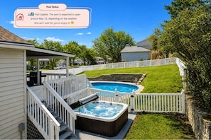A backyard with a hot tub, a swimming pool, and a covered patio area.