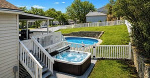Un jardin avec un jacuzzi, une piscine et un espace patio couvert.