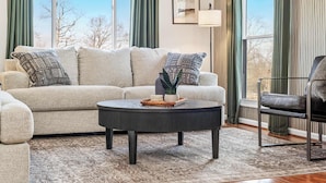 Un salon avec un canapé, une table basse et un fauteuil.