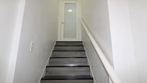A narrow, white-walled stairway with a wooden handrail and a door at the top. - Cozy Studio - Centrally Located - Free Parking (Orlando)