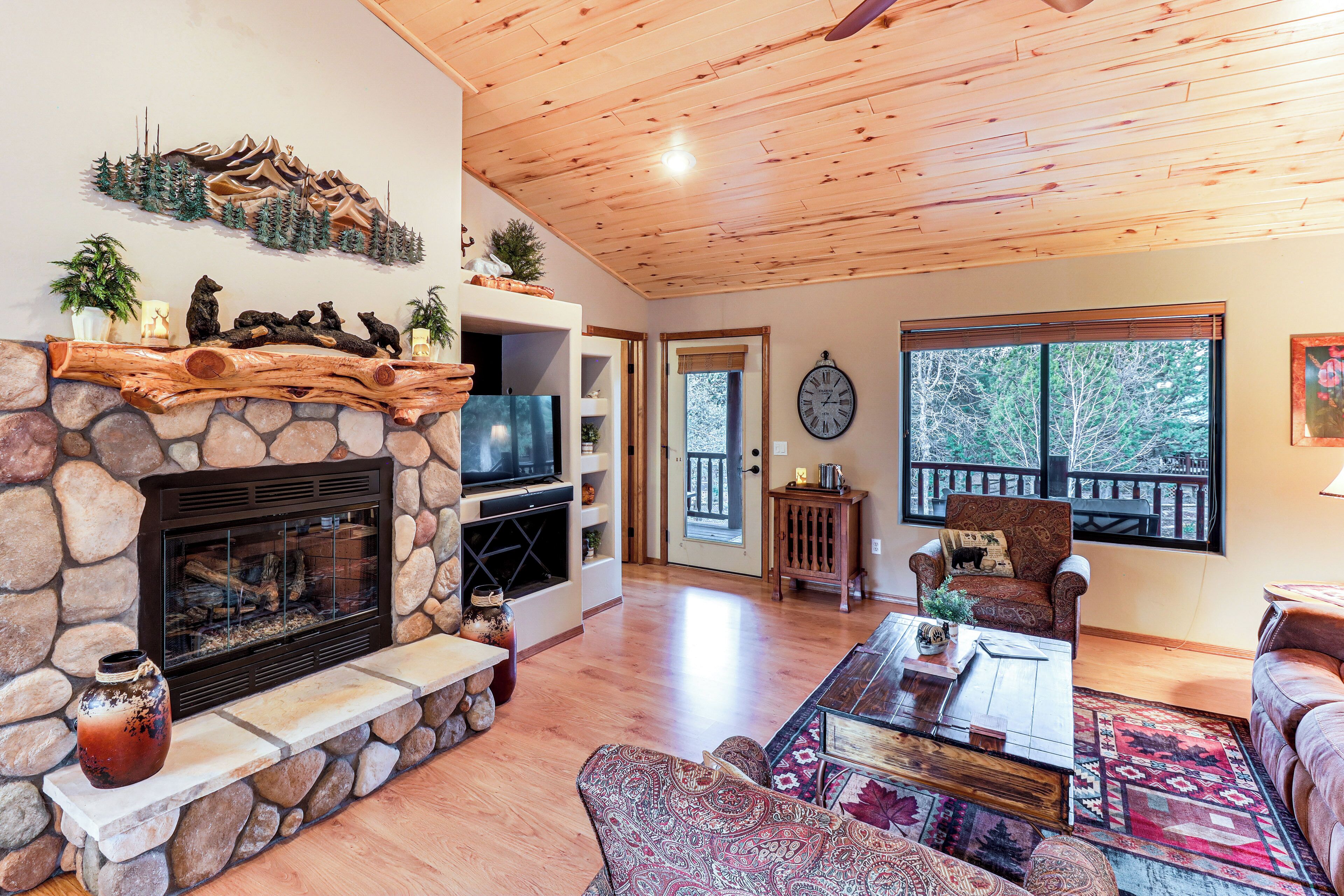 A living room with a stone fireplace, a television, a coffee table, and a sofa.