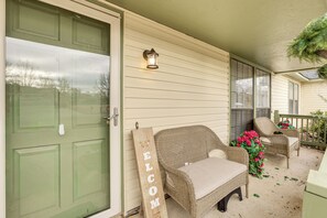 A porch with wicker chairs, a welcome sign, and a lantern.