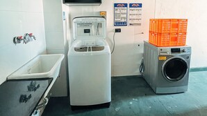 Een praktische ruimte met een wasmachine, een spoelbak en een televisie aan de muur.