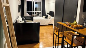 Een kleine hotelkamer met een bed, bureau en een zithoek.