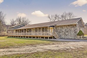 A long, single-story building with a covered porch and a stone wall.
