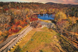 A large body of water surrounded by trees with autumn foliage, a stone structure, and a paved area with bollards. - Rustic Lakefront Studio with Deck & Workspace (Monroe)