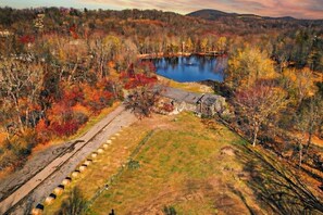 A rural landscape with a pond, a stone building, and a dirt path.