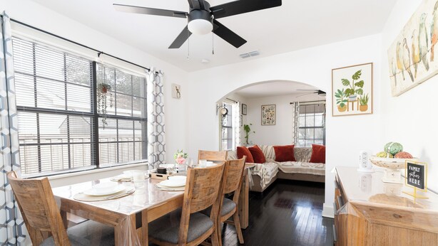 A dining area with a wooden table and chairs, a ceiling fan, and a view of the living room. - Hidden Gem Near Plaza Mall - Mi Casita McAllen (McAllen)