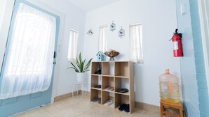A room with a blue door, a white potted plant, a wooden shoe rack, a red fire extinguisher, and a large water dispenser. - Hidden Gem Near Plaza Mall - Mi Casita McAllen (McAllen)