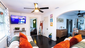 A living room with a flat-screen TV, a ceiling fan, and a dining area with a wooden table and chairs. - Hidden Gem Near Plaza Mall - Mi Casita McAllen (McAllen)