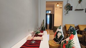 Un comedor con mantel a rayas, muebles de mimbre y cojines con motivos tropicales.