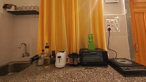 Una cocina con encimera de granito, hervidor, tostadora, portalapices verde, fregadero y toma de corriente.
