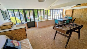 A room with a bed, a foosball table, a dining table, and a view of the outside. - La Bonne Ecole - La Marelle Vacation Rental - Sleeps 7 - 20 min from Puy du Fou - (Les Landes-Genusson)