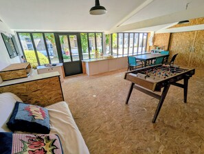 Une chambre avec un lit, une table de baby-foot, une table à manger et une vue sur l’extérieur.