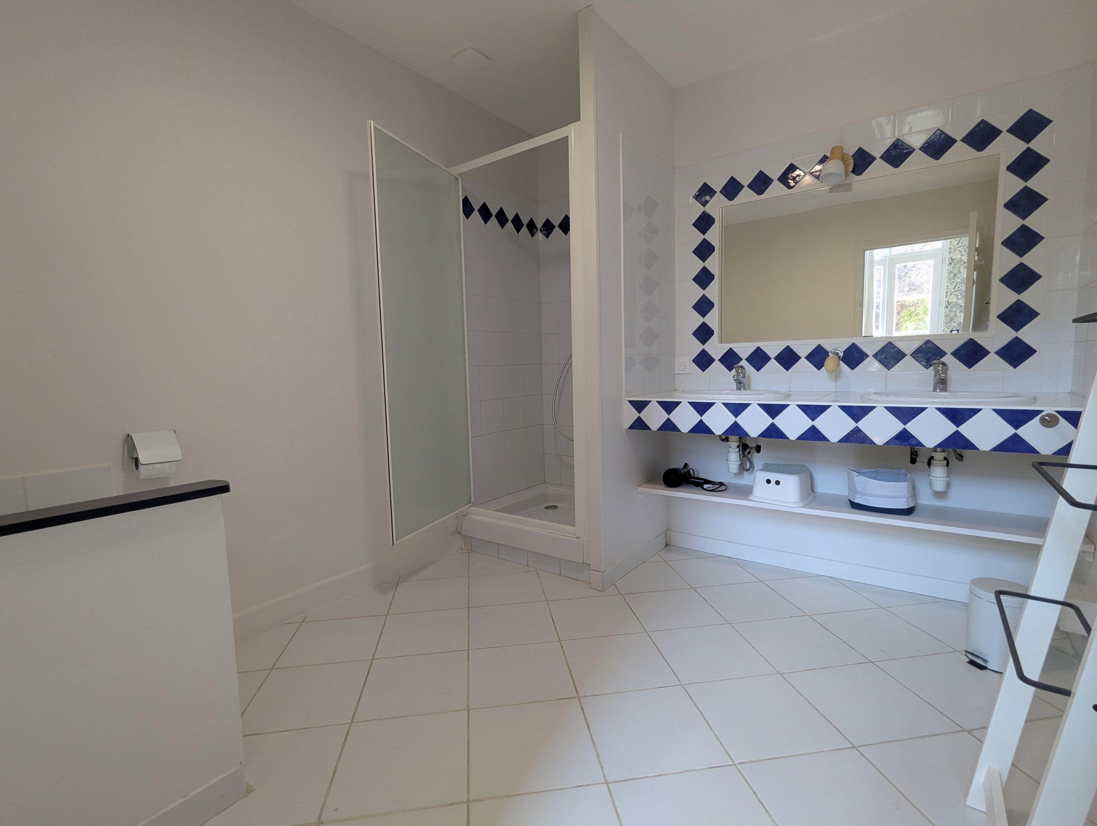 Un baño con ducha, lavamanos y espejo.