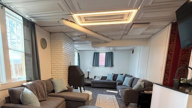 Een moderne woonkamer met een modulaire bank, een ronde salontafel en een flatscreen televisie.