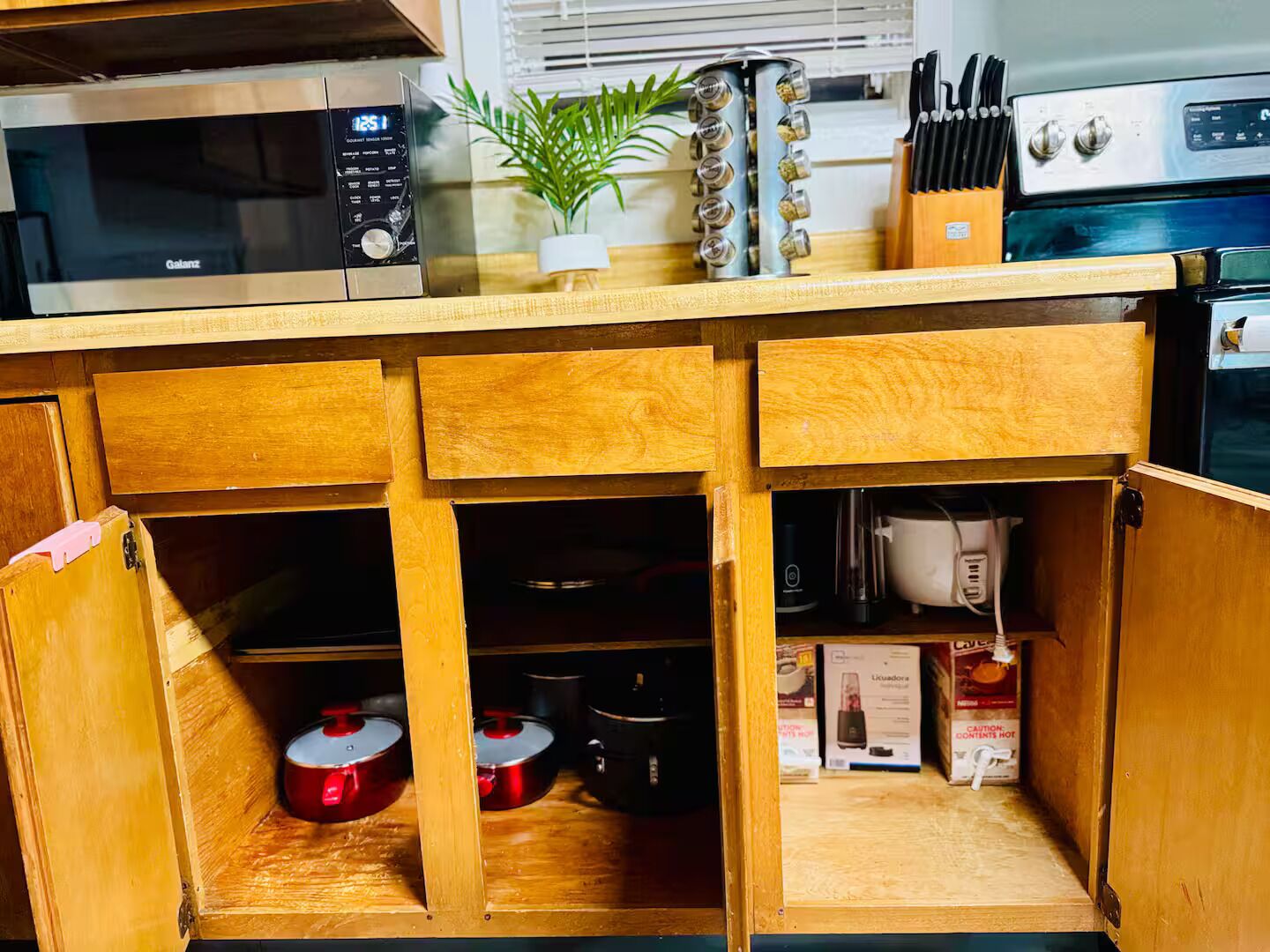 A kitchen with wooden cabinets, a microwave, a stove, and various kitchen utensils.