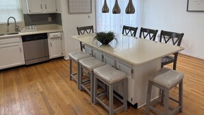 A modern kitchen with white cabinets, a dishwasher, and a dining area with a large table and six chairs. - Cozy Gameroom 
4BR/3b Townhouse by the Lake - Gaithersburg, Maryland (Gaithersburg)