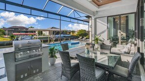 Patio esterno con barbecue, mobili in vimini e piscina.