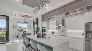 Una cucina moderna con un'isola grande, sgabelli da bar e forno integrato.