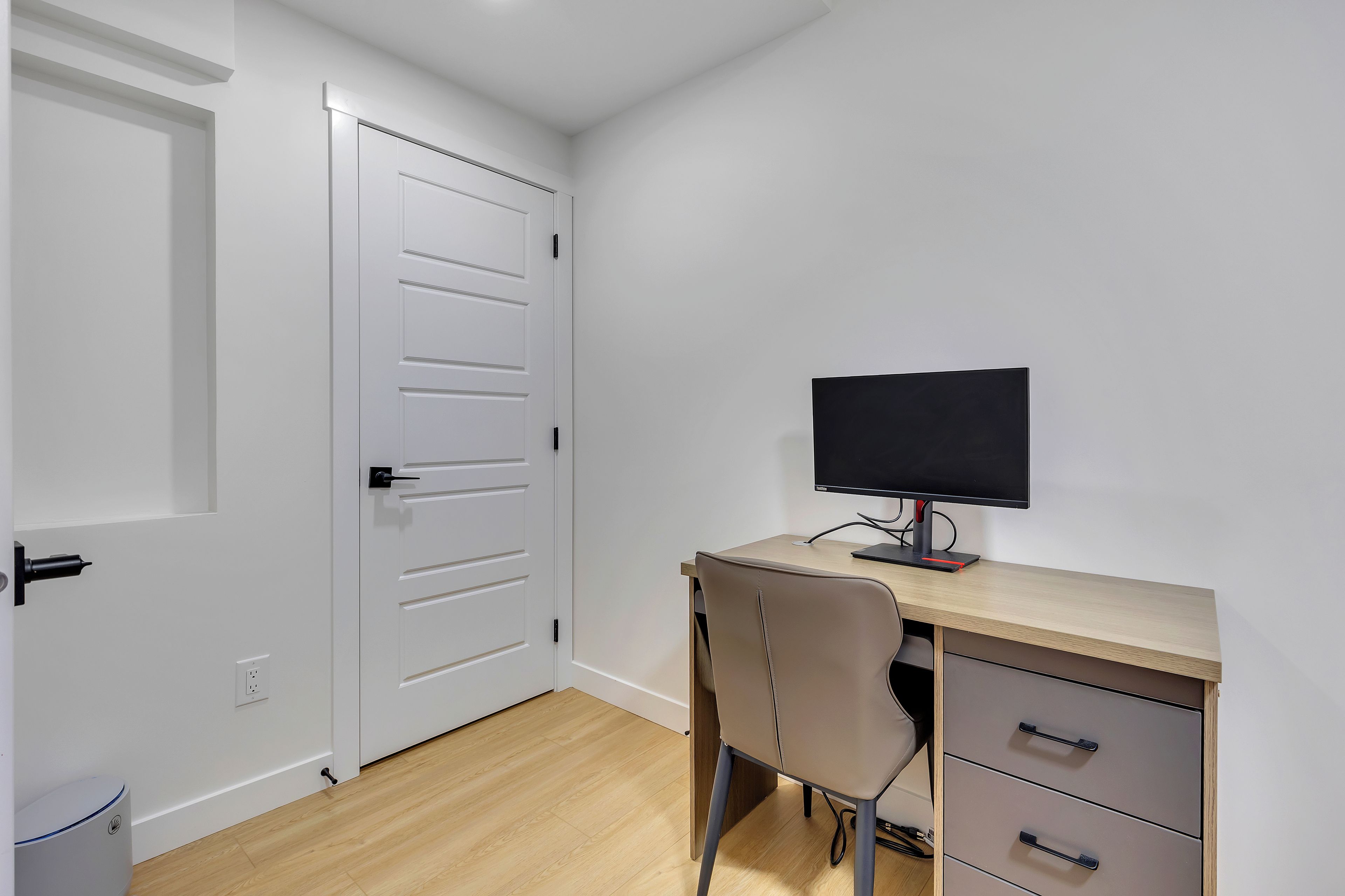 A room with a desk, chair, and a closed door.
