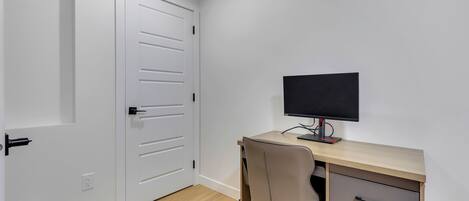 A room with a desk, chair, and a closed door.