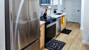 Eine moderne Küche mit Edelstahlgeräten, weißen Schränken und einer Holz Arbeitsplatte.