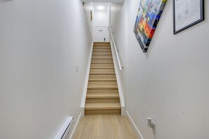 A narrow hallway with a wooden staircase leading to a door at the end. - Stylish Suite by Airport/Fast Wi-Fi/Free Driveway Parking/Sleeps 4/Self Check-in (Calgary)